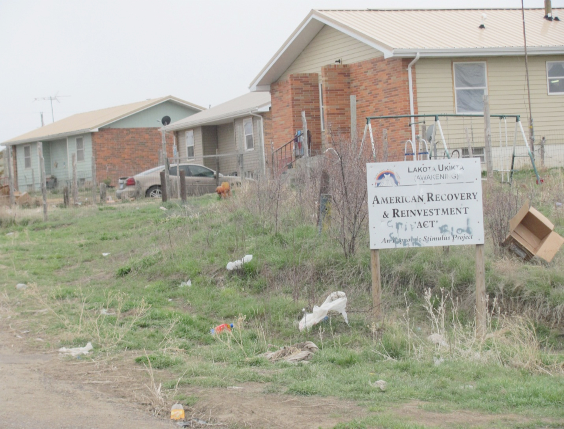 The sign in front of this housing cluster at Wounded Knee symbolizes the longstanding ineffectiveness of government at Pine Ridge. 